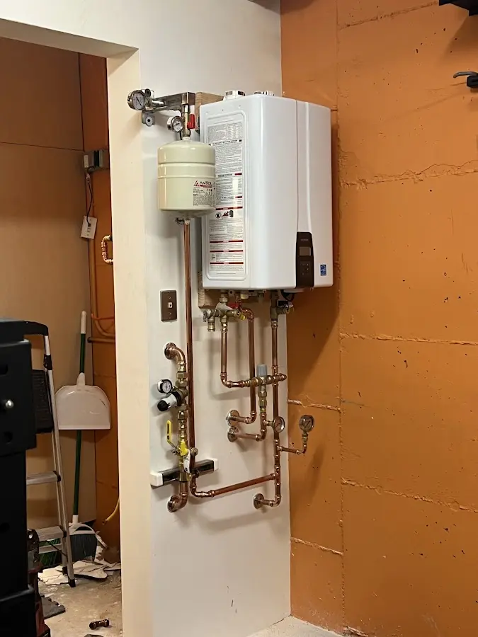 Plumbing technician inspecting water heater connections in Falls